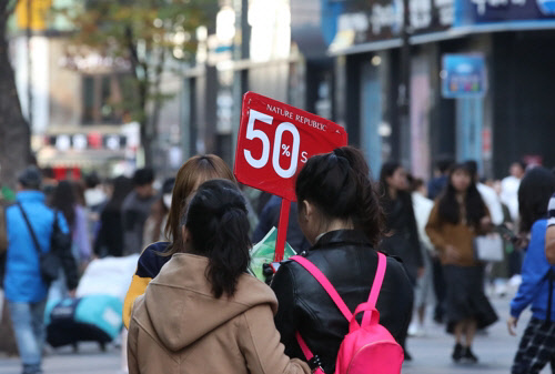 코리아세일페스타가 시작된 지난 1일 오후 서울 중구 명동 쇼핑가에서 한 상점 직원이 50% 할인을 알리는 푯말을 들고 있다. <연합 제공>